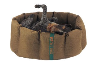 Happy dog on its back in nest dog bed